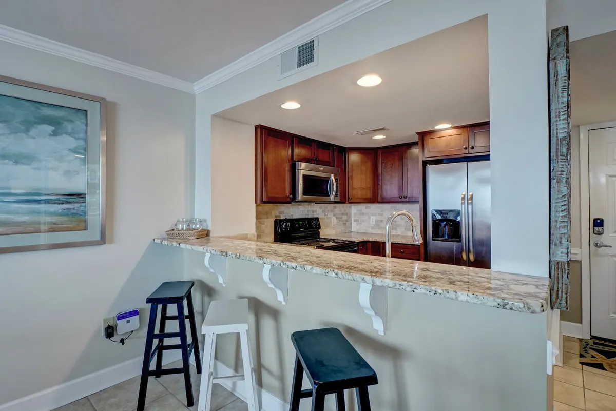 A welcoming kitchen island with stools, stainless steel appliances, and framed artwork. The open-plan space is perfect for casual dining, cooking together, or socializing while preparing meals.