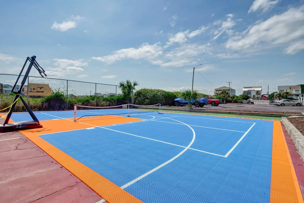 An exterior shot showcasing a vibrant, multi-use sports court equipped for basketball and tennis, surrounded by resort buildings. The space is ready for friendly competitions and energetic gatherings anytime.