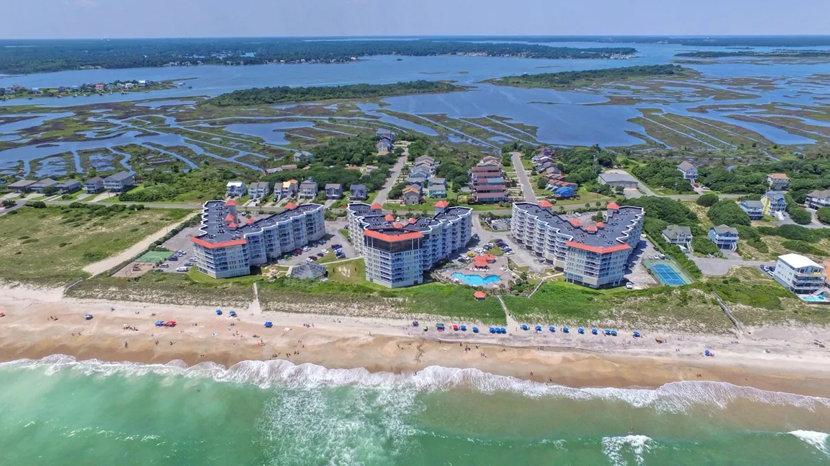 A wide-angle exterior view of the resort’s beachfront location, featuring a large swimming pool, beach umbrellas, and the ocean in the background. The pool area signals relaxation, while the oceanfront setting promises memorable group experiences.